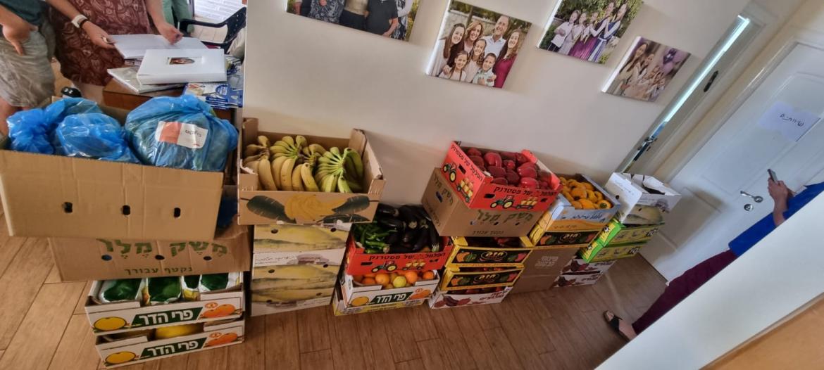 תוצרת חקלאית מהבקעה מונחת ברצפה בתוך ארגזים בבית משפחת די , בקיר תמונות של המשפחה